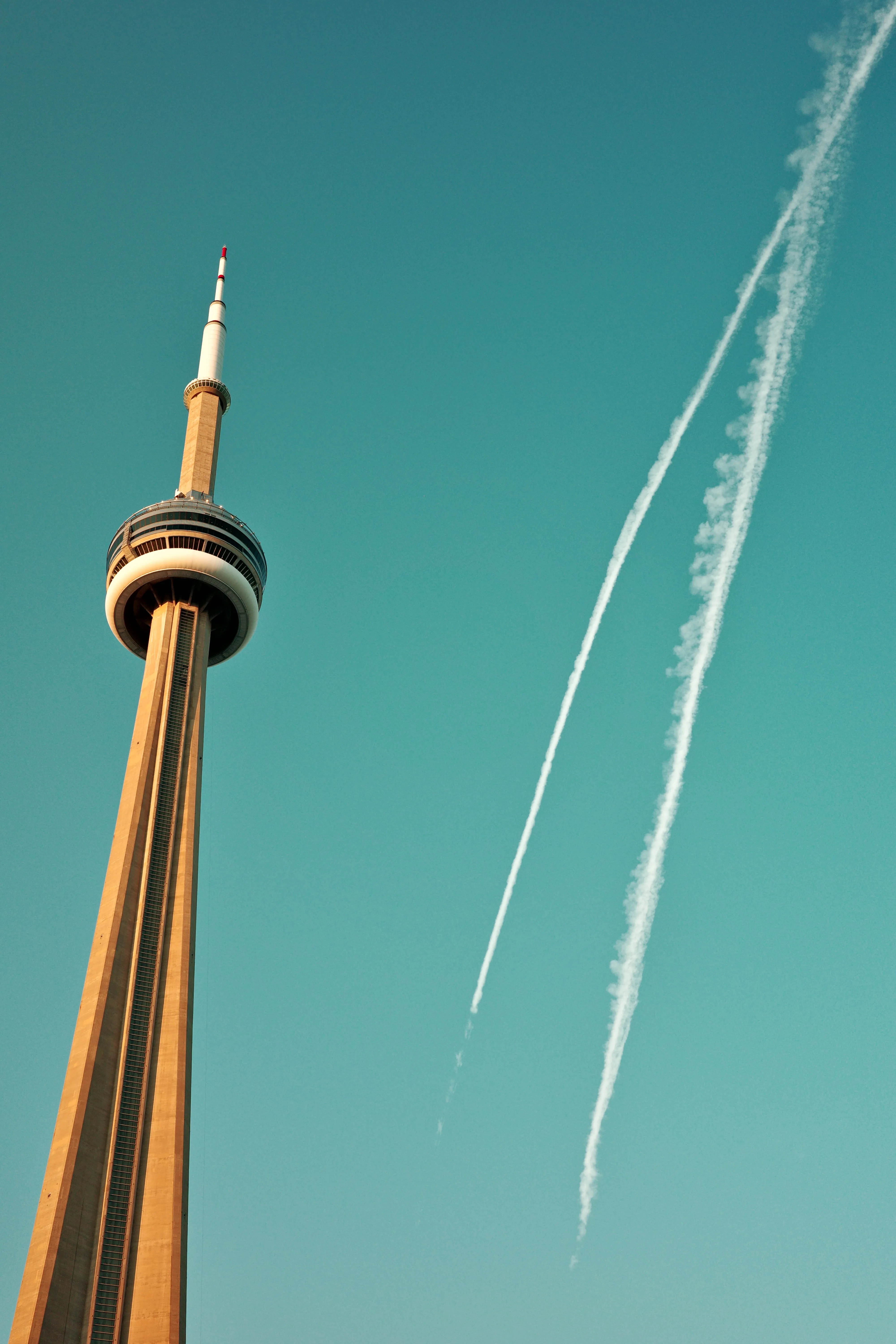 Photo of CN Tower next to some contrails